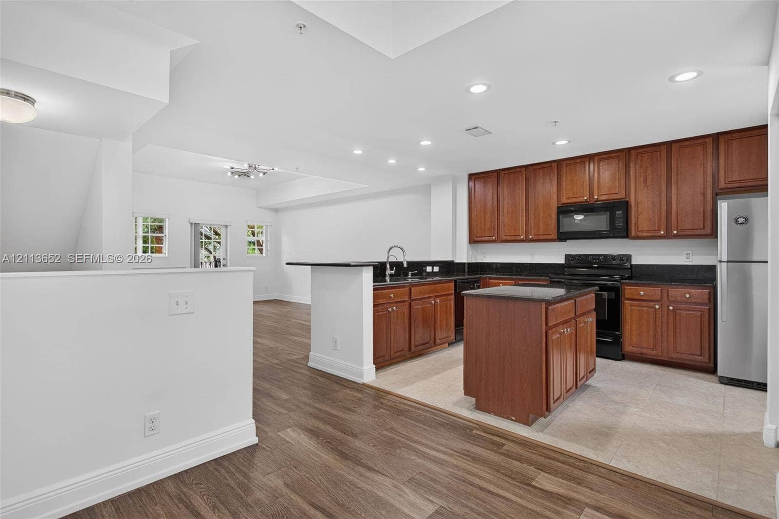 618 SW 1st Lane, Pompano Beach, FL 33060 Kitchen featuring wood cabinetry, stone countertops, central island, integrated stainless steel appliances, and wood-finish flooring