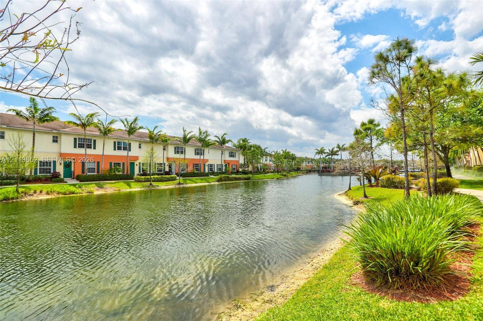618 SW 1st Lane, Pompano Beach, FL 33060 Waterfront townhouse exterior featuring a two-story stucco facade, decorative shutters, and manicured landscaping with mature palm trees