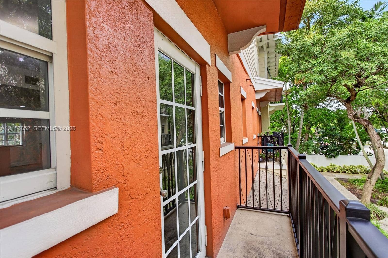 618 SW 1st Lane, Pompano Beach, FL 33060 Exterior balcony featuring stucco walls, a multi-pane glass entry door, and a black metal railing