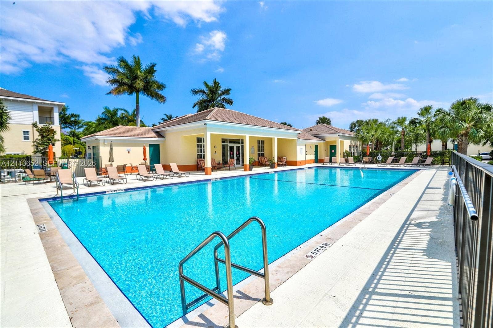 618 SW 1st Lane, Pompano Beach, FL 33060 Rectangular swimming pool with metal ladder entry, surrounded by a light-toned concrete deck and an encompassing metal perimeter fence
