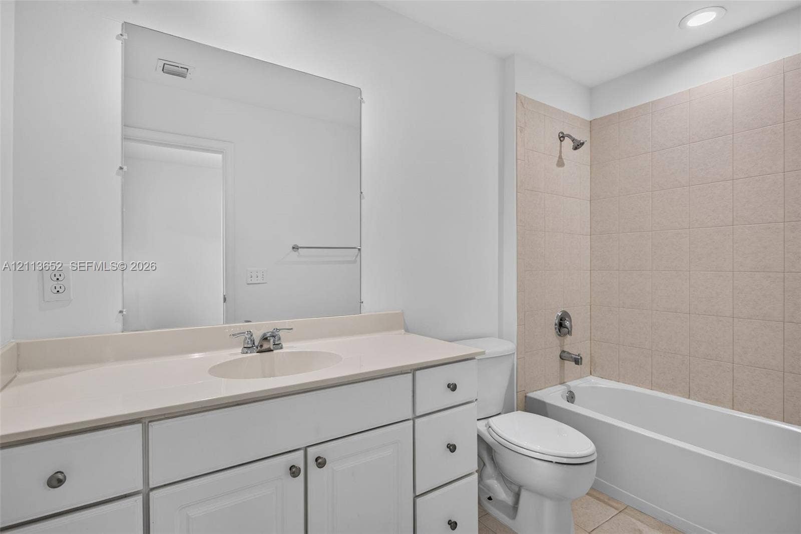 618 SW 1st Lane, Pompano Beach, FL 33060 Bathroom featuring a white vanity with integrated basin, expansive wall-mounted mirror, recessed lighting, and a bathtub with tile surround