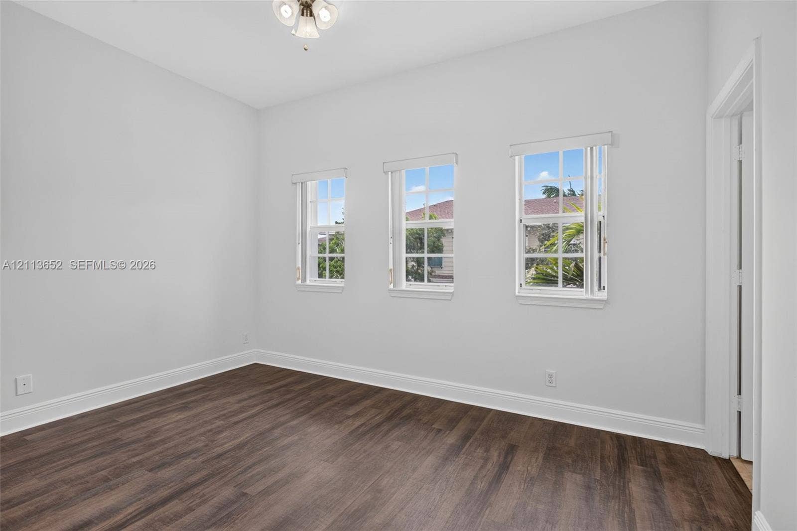 618 SW 1st Lane, Pompano Beach, FL 33060 Interior room featuring wood-finish flooring, three double-hung windows, and a flush-mount light fixture