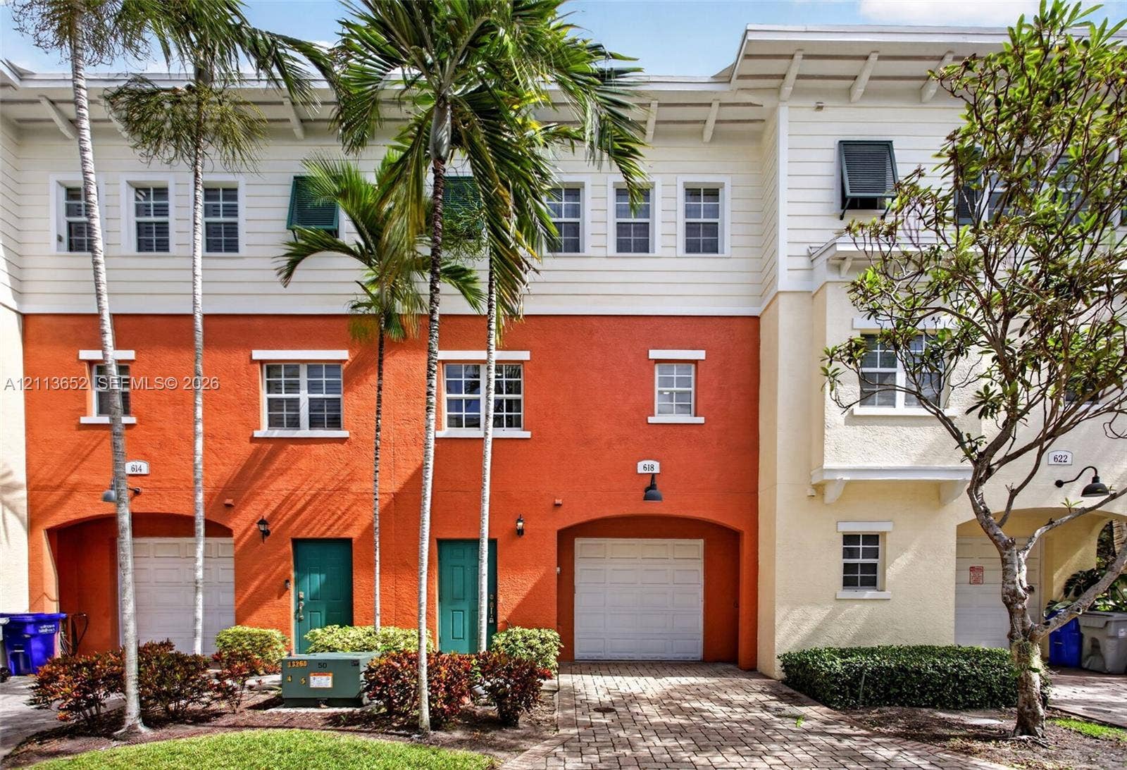 618 SW 1st Lane, Pompano Beach, FL 33060 Multi-story exterior featuring a textured stucco facade, integrated single-car garages, and an overhead roofline with exposed rafters