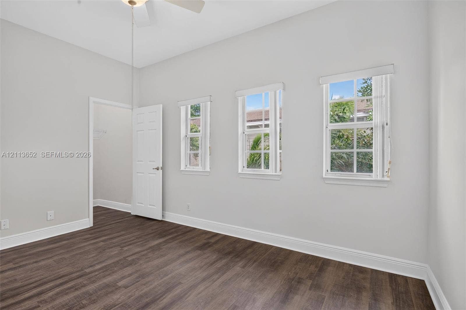 618 SW 1st Lane, Pompano Beach, FL 33060 Room featuring wood-finish flooring, three grid-pane windows, and a white six-panel door