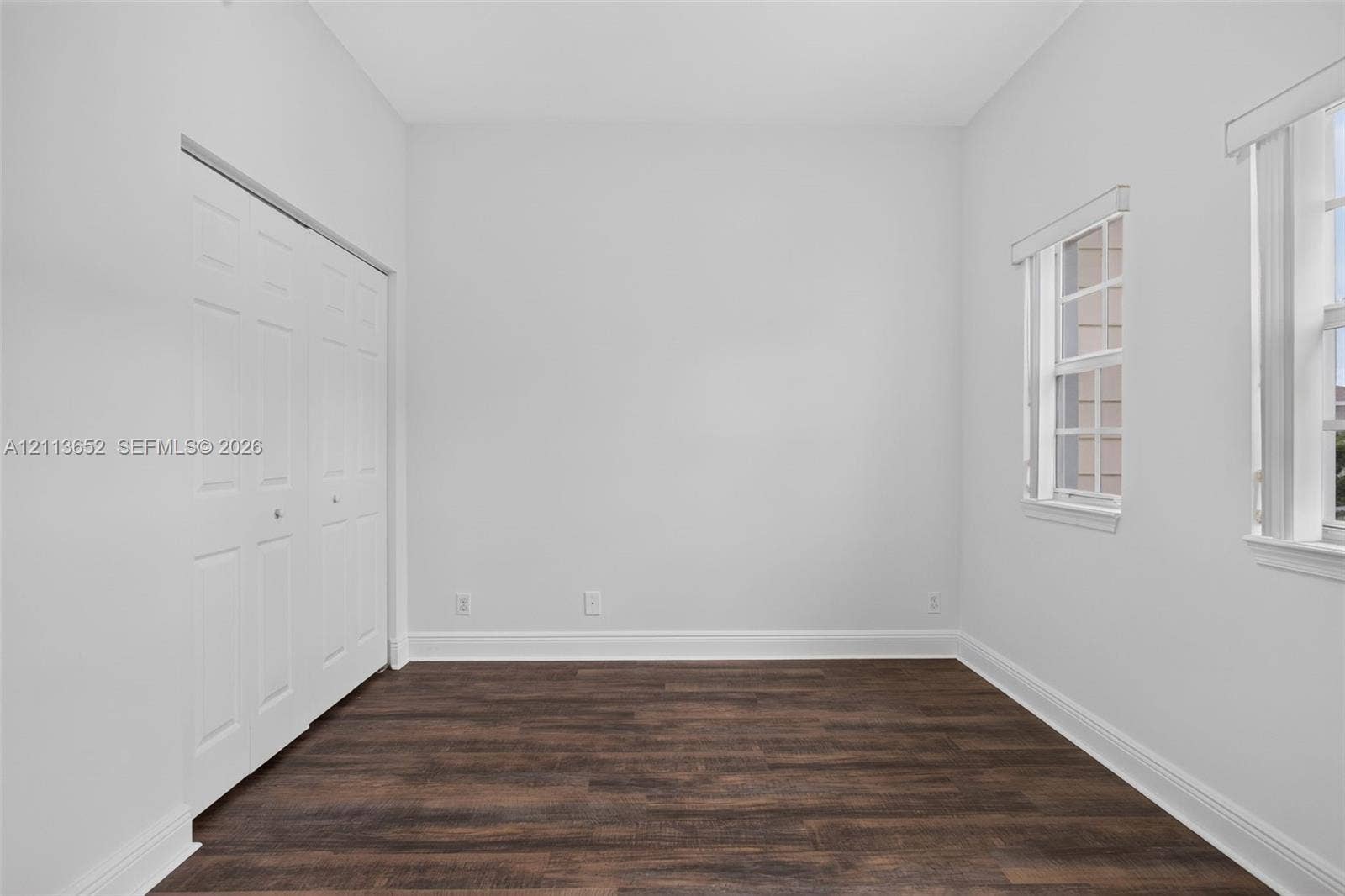 618 SW 1st Lane, Pompano Beach, FL 33060 Room featuring wood-finish flooring, neutral walls, double-door closet, and dual windows