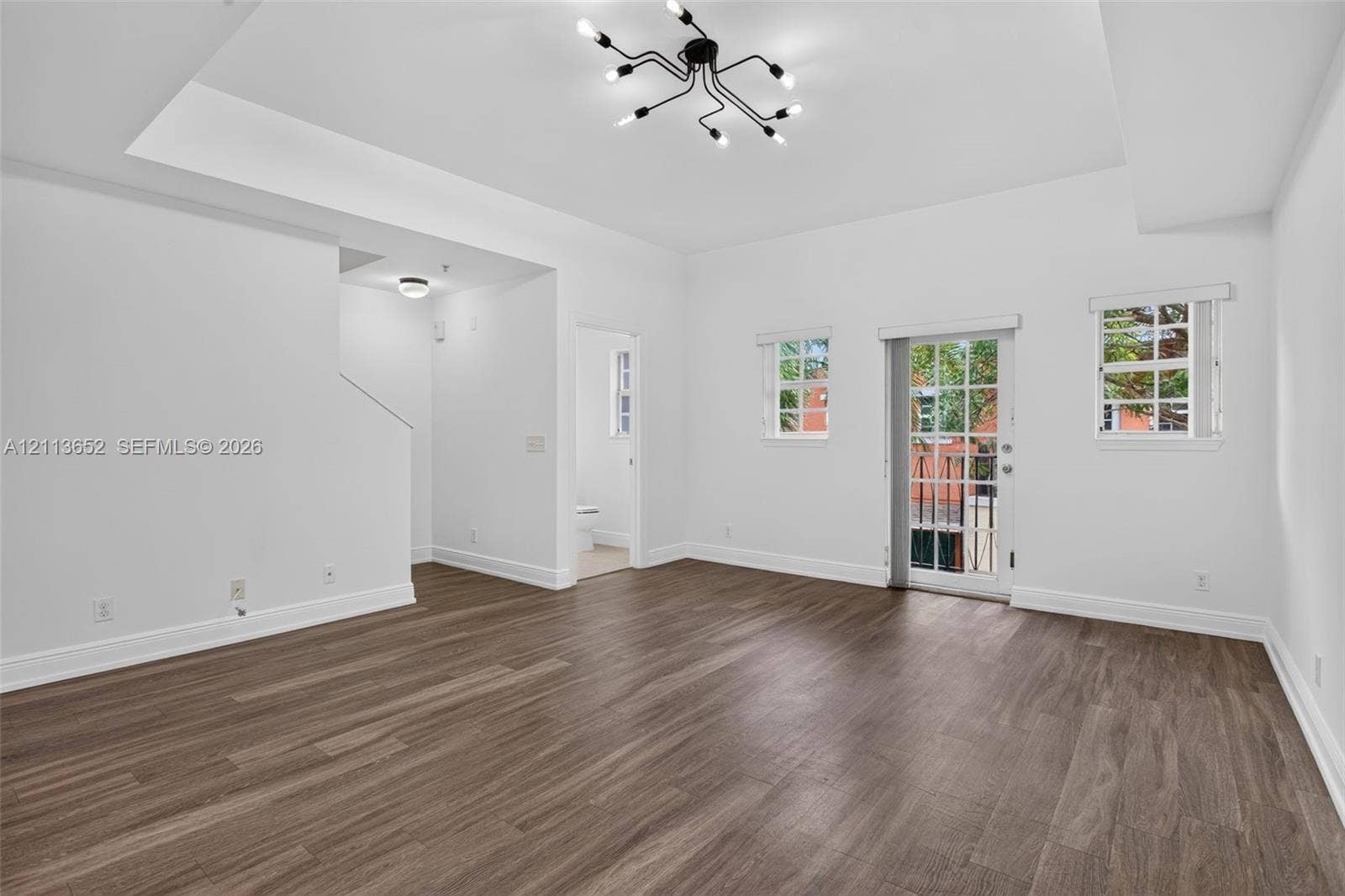 618 SW 1st Lane, Pompano Beach, FL 33060 Living area featuring wood-finish flooring, a tray ceiling, a multi-arm modern chandelier, and a glass-paneled door