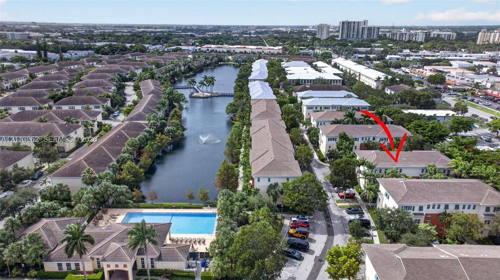 618 SW 1st Lane, Pompano Beach, FL 33060 Aerial perspective of residential community featuring a multi-story building, an expansive water feature with a fountain, a swimming pool, and mature palm trees