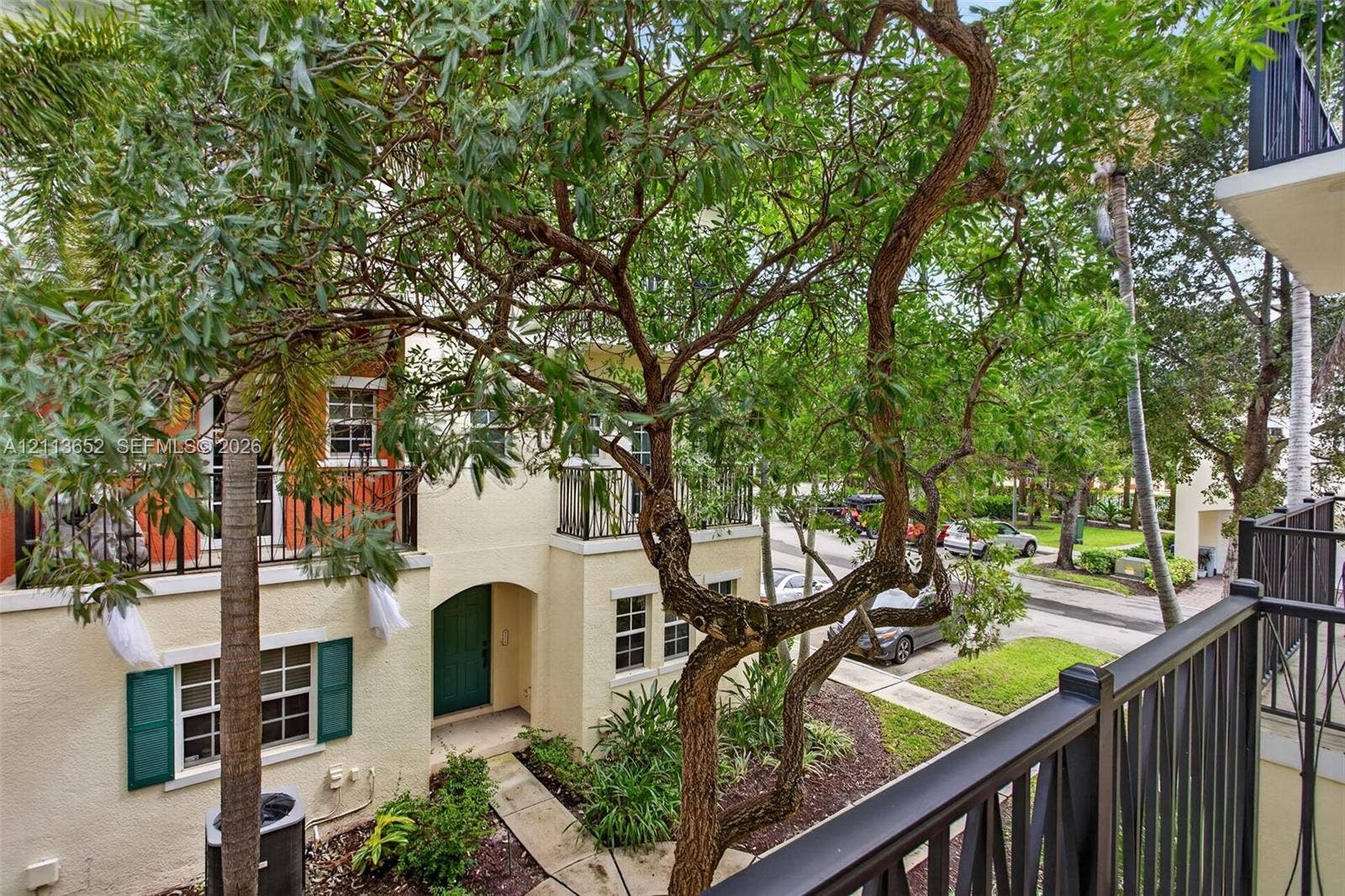 618 SW 1st Lane, Pompano Beach, FL 33060 Stucco exterior with decorative green shutters, wrought iron balcony railings, arched entryway, and mature landscaping