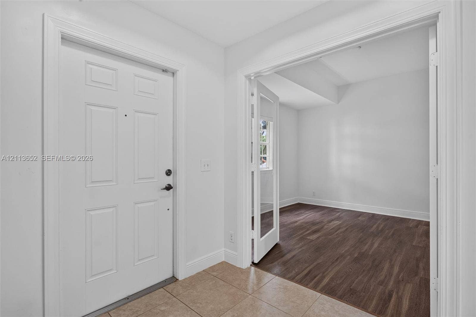 618 SW 1st Lane, Pompano Beach, FL 33060 Entryway featuring neutral tile flooring, a multi-panel door with metallic hardware, and French doors opening to an area with wood-finish flooring