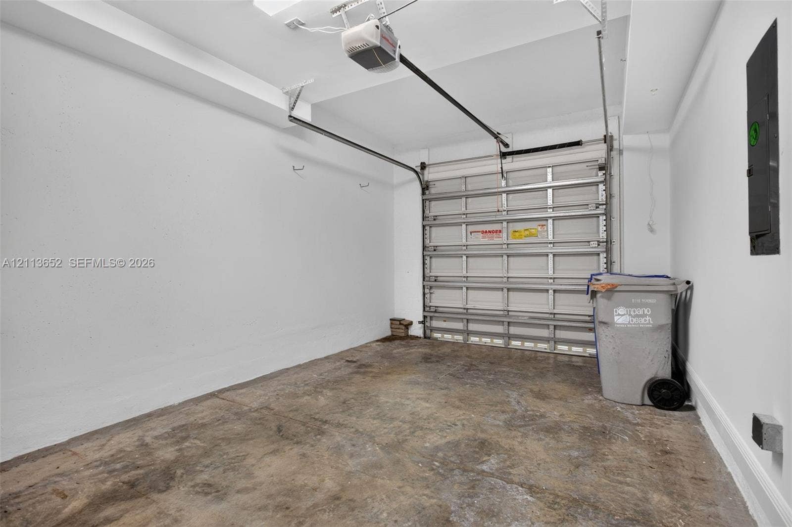 618 SW 1st Lane, Pompano Beach, FL 33060 Enclosed garage featuring painted white walls, a metal roll-up door, and an automated door opener
