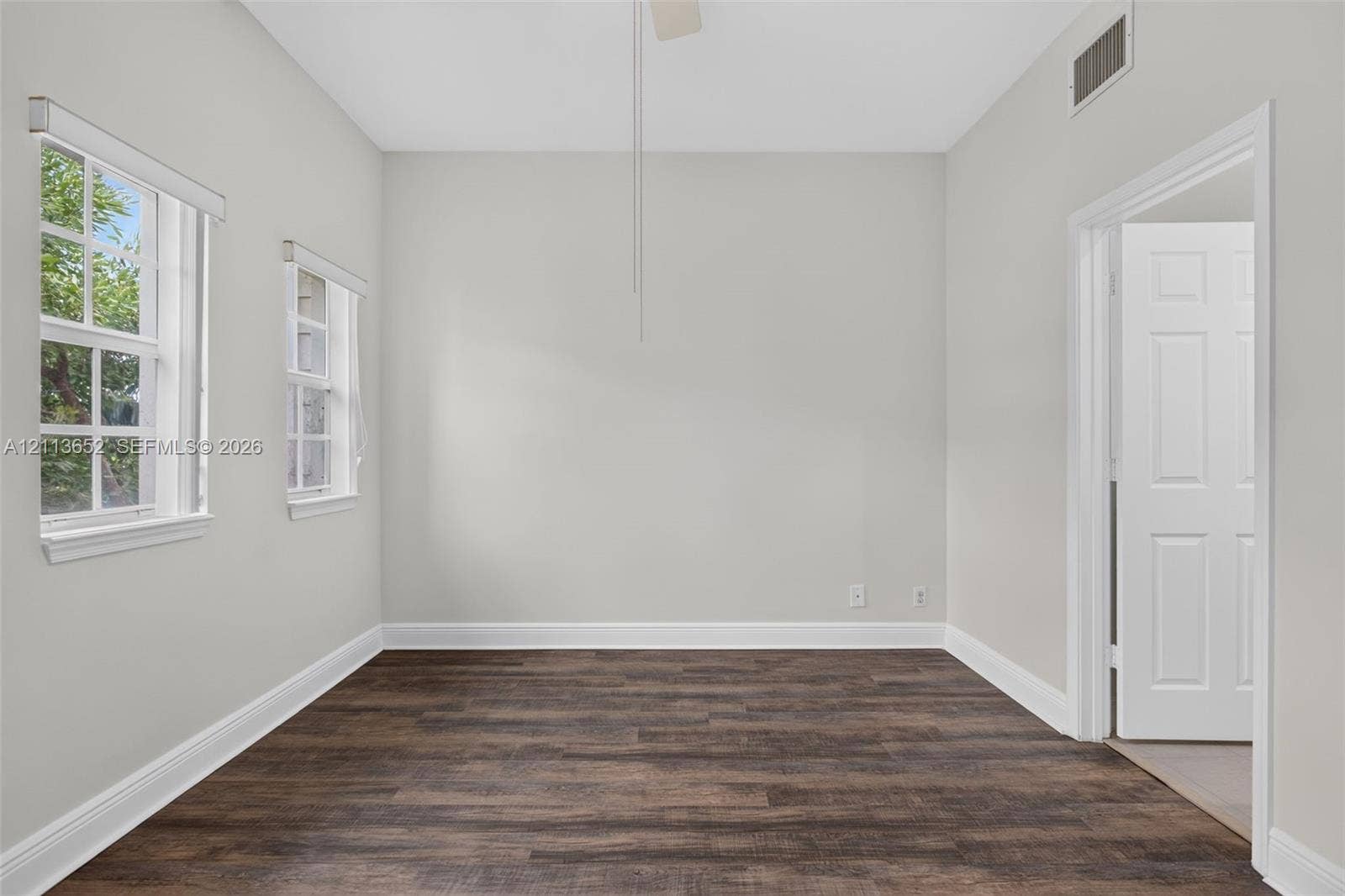 618 SW 1st Lane, Pompano Beach, FL 33060 Room featuring wood-finish flooring, neutral wall paint, two multi-pane windows, and a classic six-panel door