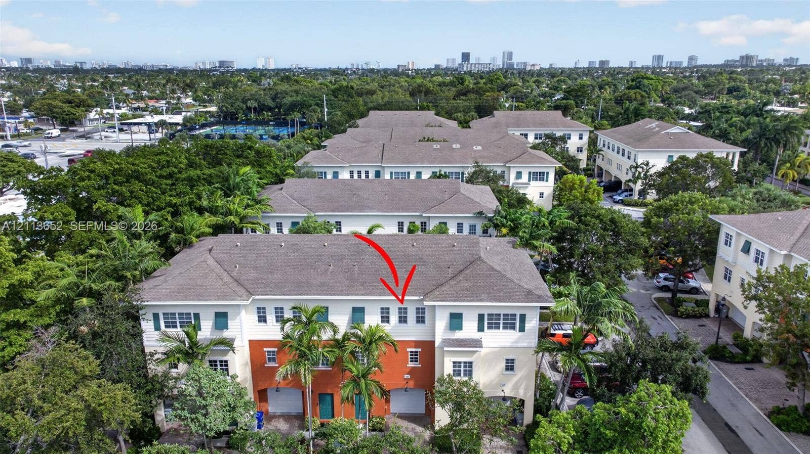 618 SW 1st Lane, Pompano Beach, FL 33060 Multi-story townhouse exterior featuring a high-contrast stucco facade, attached garage, shingled hip roof, and surrounding mature landscaping