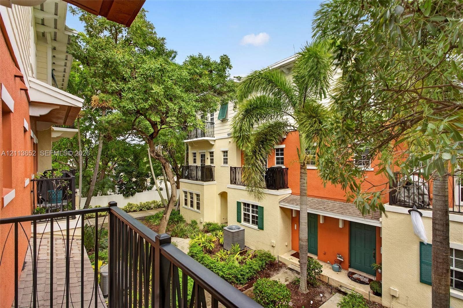 618 SW 1st Lane, Pompano Beach, FL 33060 Multi-level exterior featuring stucco siding, wrought-iron balcony railings, arched architectural details, mature landscaping, and paver walkways