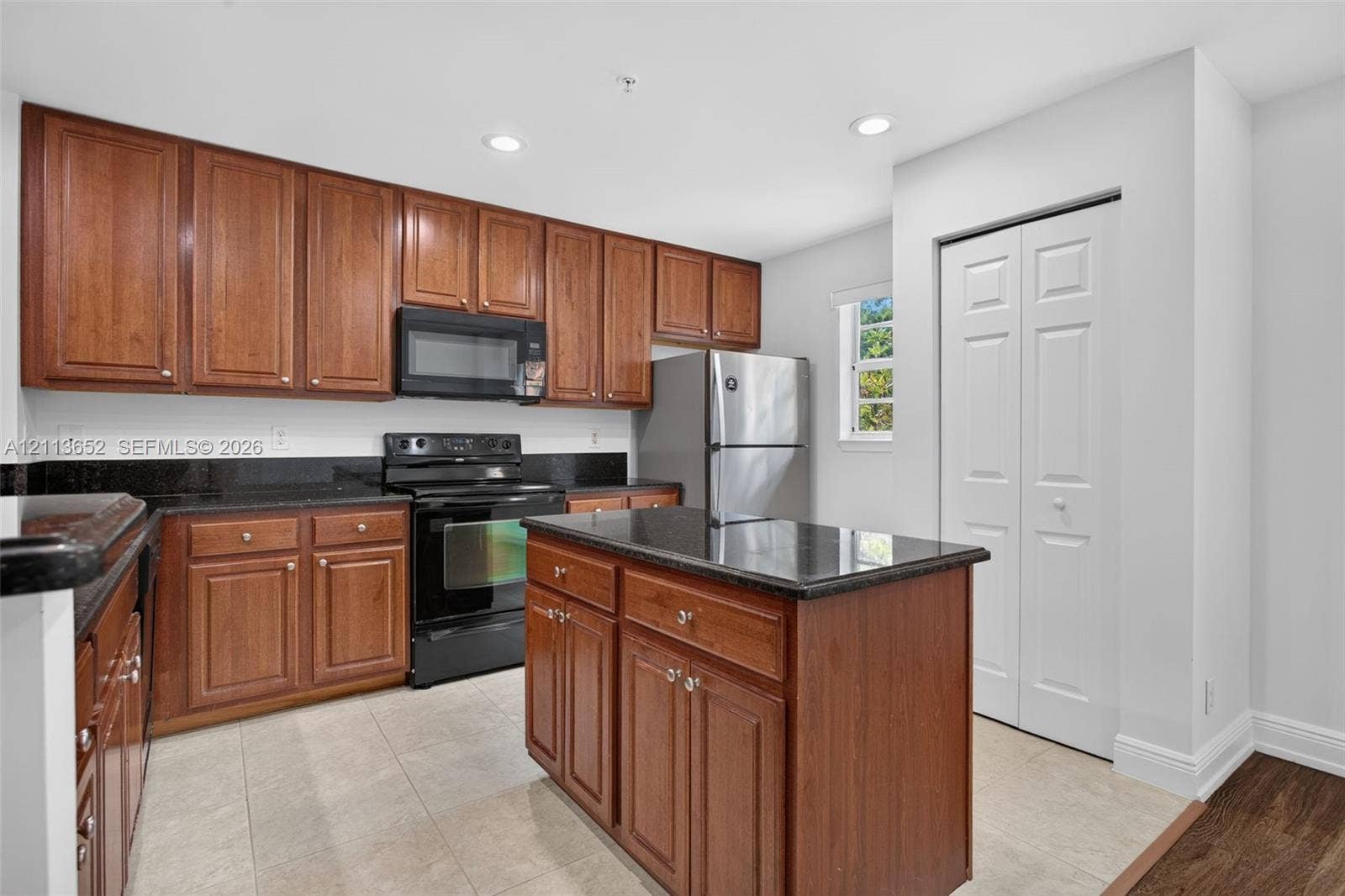 618 SW 1st Lane, Pompano Beach, FL 33060 Kitchen featuring wood cabinetry, stone-surface countertops, central island, stainless steel appliances, and tile flooring