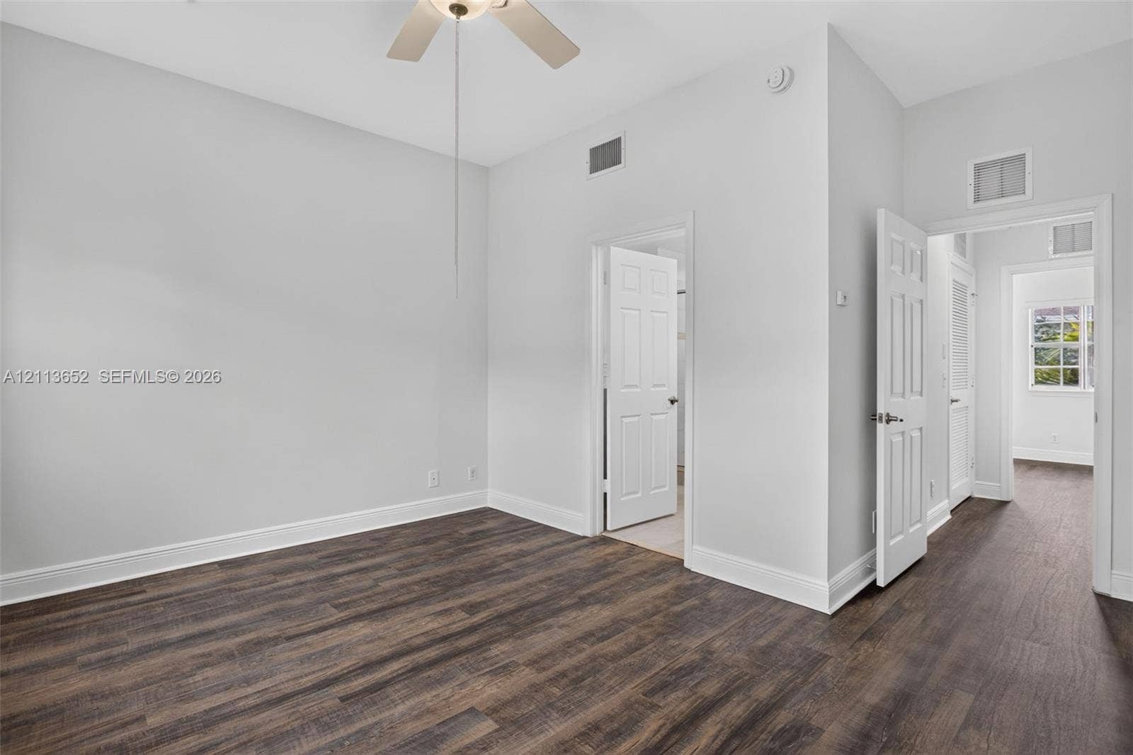 618 SW 1st Lane, Pompano Beach, FL 33060 Interior room featuring wood-finish flooring, neutral wall paint, a ceiling fan, and multiple six-panel interior doors