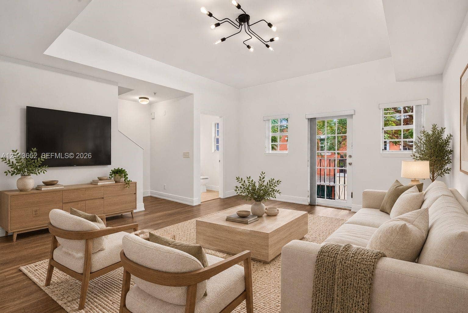 618 SW 1st Lane, Pompano Beach, FL 33060 Living area featuring a tray ceiling, wood-finish flooring, multi-arm sputnik lighting fixture, and a glass-paneled exterior door