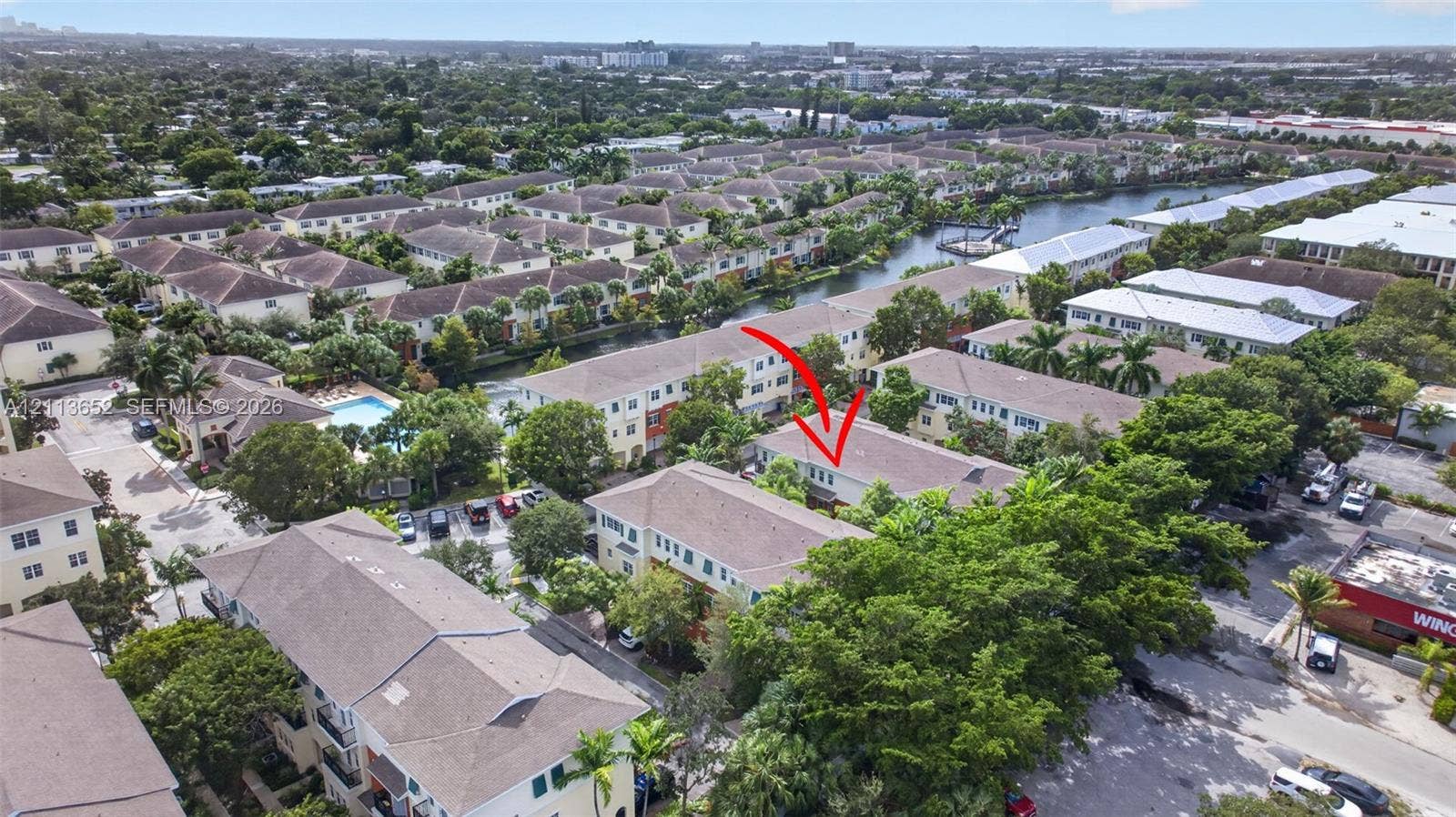 618 SW 1st Lane, Pompano Beach, FL 33060 Aerial perspective of a multi-story residential building featuring a shingled roof, light-toned exterior finish, and established landscape foliage