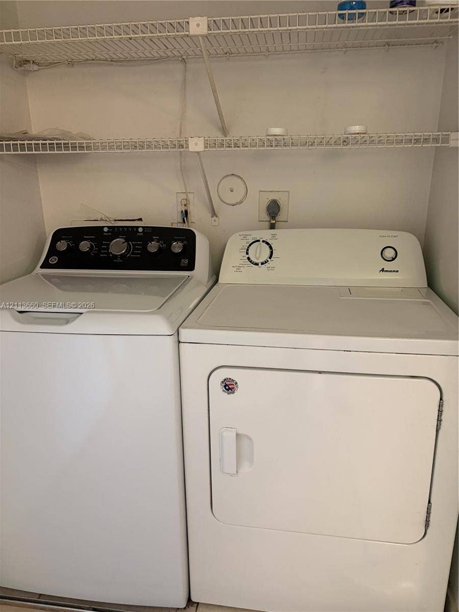 Laundry area featuring a top-loading washing machine, electric dryer, and dual-tier wire shelving
