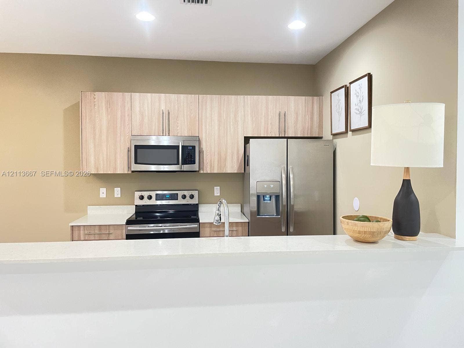 Kitchen featuring flat-panel wood-finish cabinetry, stainless steel appliances, and solid surface countertops