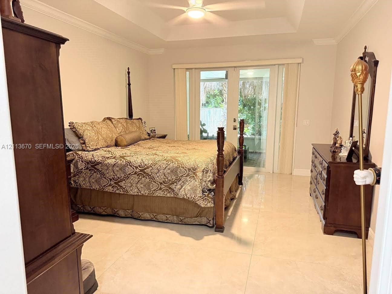 Tray ceiling with integrated crown molding, polished tile flooring, and glass sliding doors