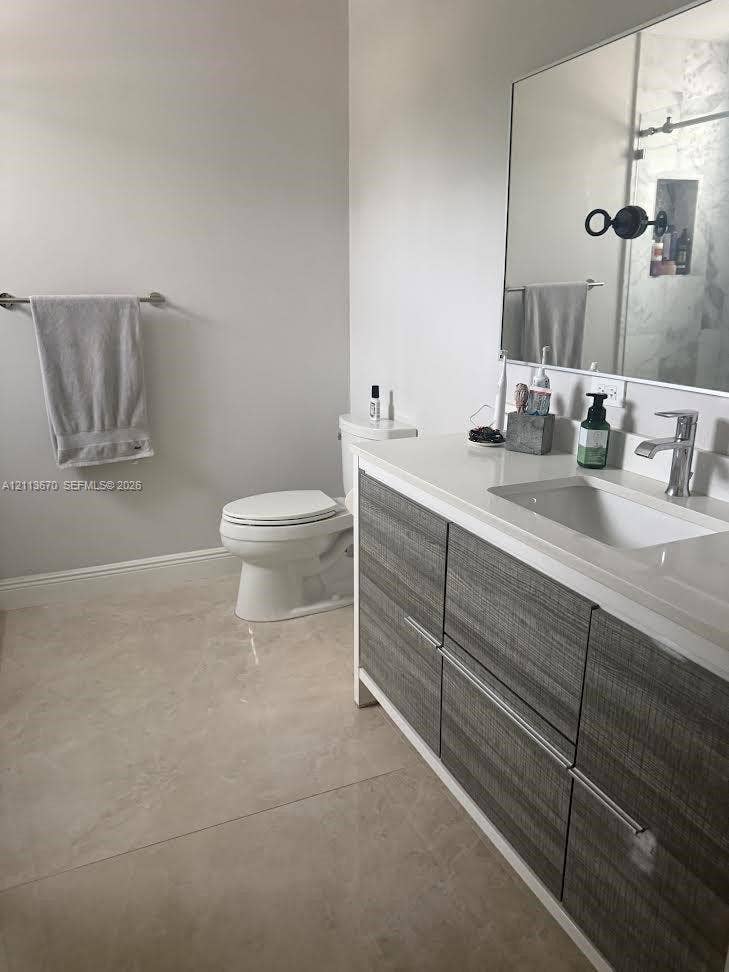 Modern vanity with wood-grain cabinetry, solid surface countertop, rectangular under-mount sink, chrome faucet, and expansive wall-mounted mirror