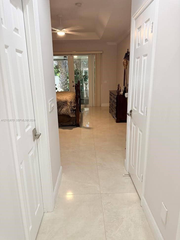 Hallway featuring large-format tile flooring, a tray ceiling, and dual six-panel interior doors