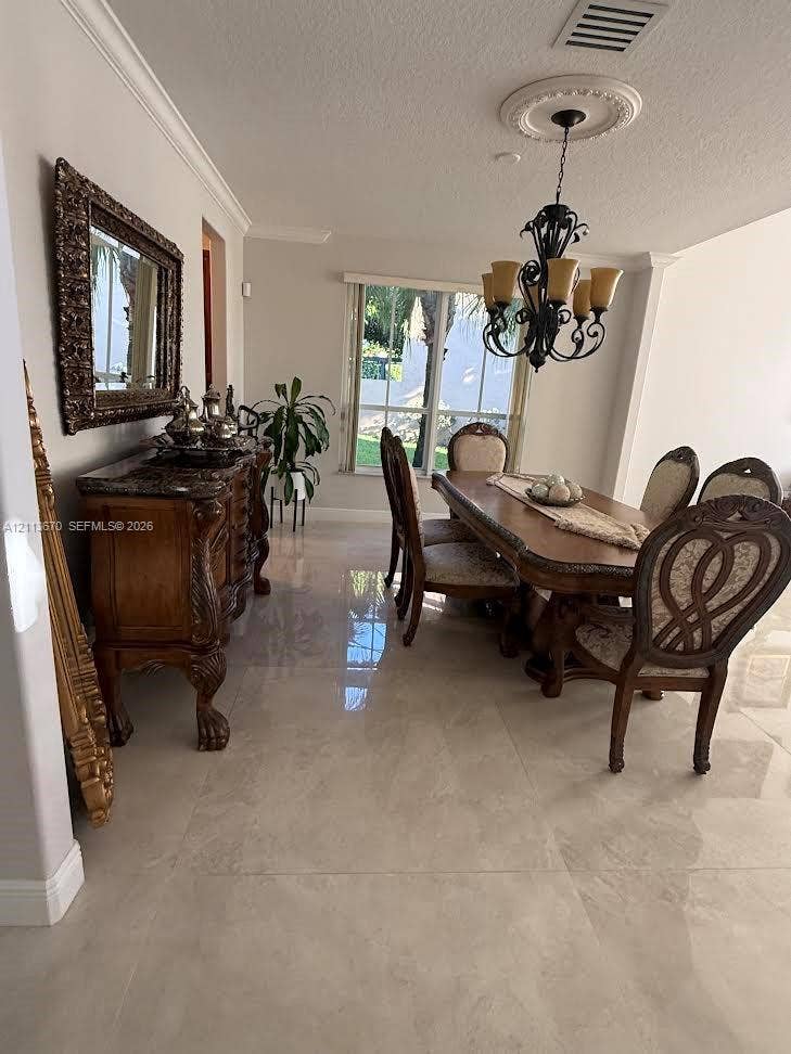 Dining area featuring polished large-format tile flooring, crown molding, a decorative ceiling medallion, and a multi-arm metal chandelier