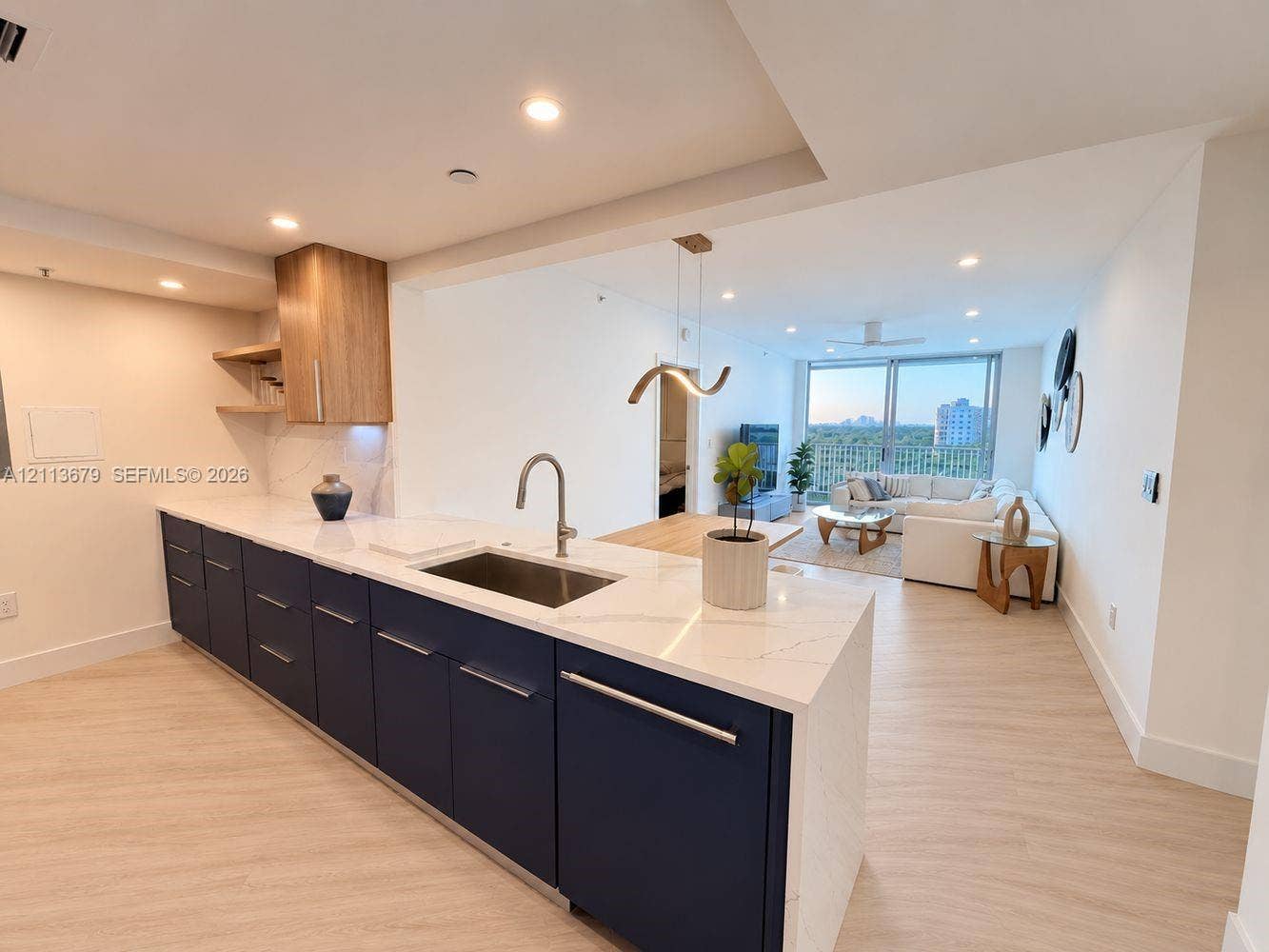 3020 NE 32nd Avenue, #612, Fort Lauderdale, Fort Lauderdale, FL 33308 Kitchen featuring navy blue lower cabinetry, white stone countertops, wood-finish cabinetry accents, recessed lighting, and a stainless steel undermount sink with a gooseneck faucet