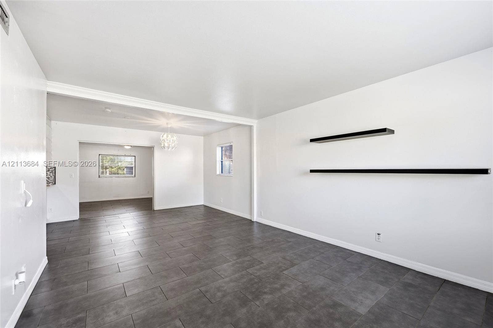 6504 Lenore Drive, Tampa, Tampa, FL 33634 Large-format tile flooring, dual matte black floating wall shelves, and a decorative crystal-style chandelier fixture