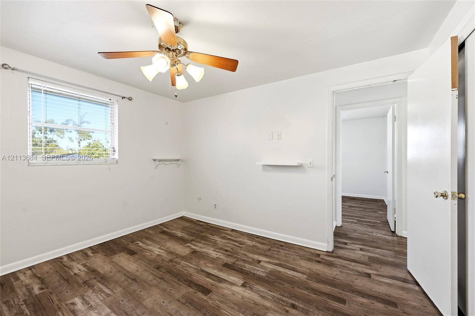 6504 Lenore Drive, Tampa, Tampa, FL 33634 Room featuring wood-finish flooring, a multi-blade ceiling fan with integrated lighting, and a window with horizontal blinds