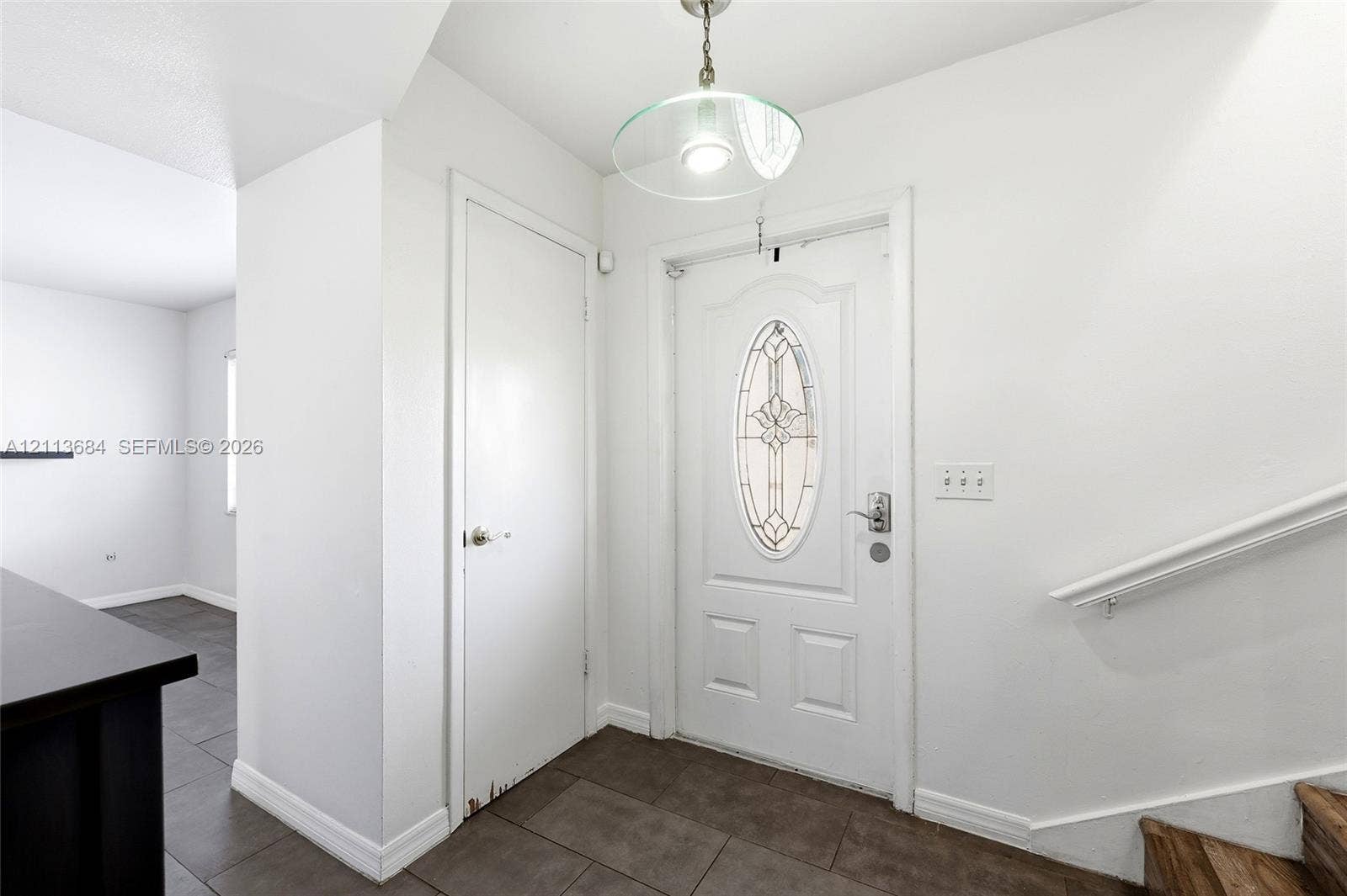6504 Lenore Drive, Tampa, Tampa, FL 33634 Entryway featuring tile flooring, a white exterior door with an oval glass insert, a pendant light fixture, and a wall-mounted handrail