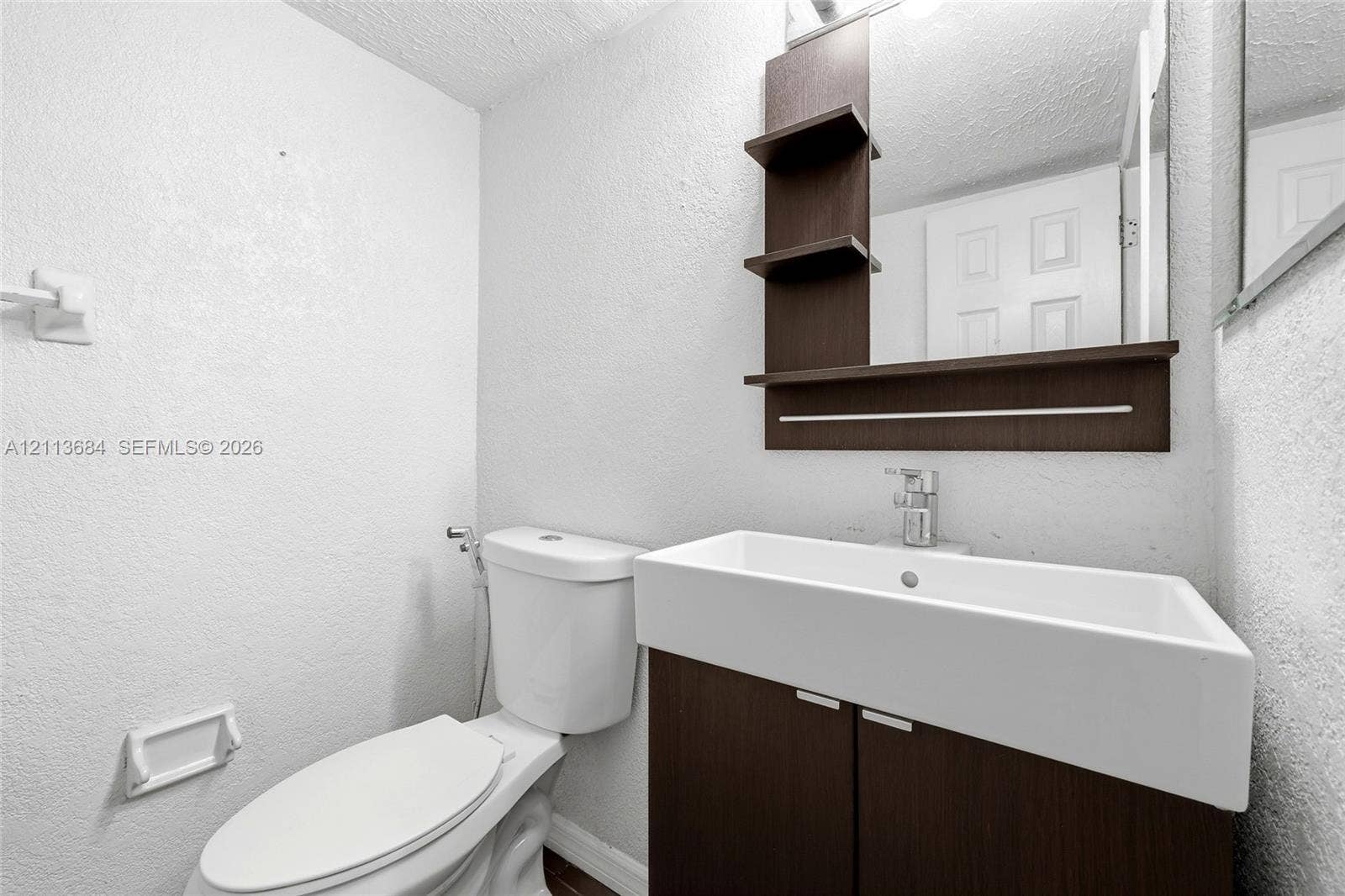 6504 Lenore Drive, Tampa, Tampa, FL 33634 Wall-mounted vanity featuring dark wood-finish cabinetry, a rectangular vessel sink, a chrome single-handle faucet, and an integrated mirror with open shelving