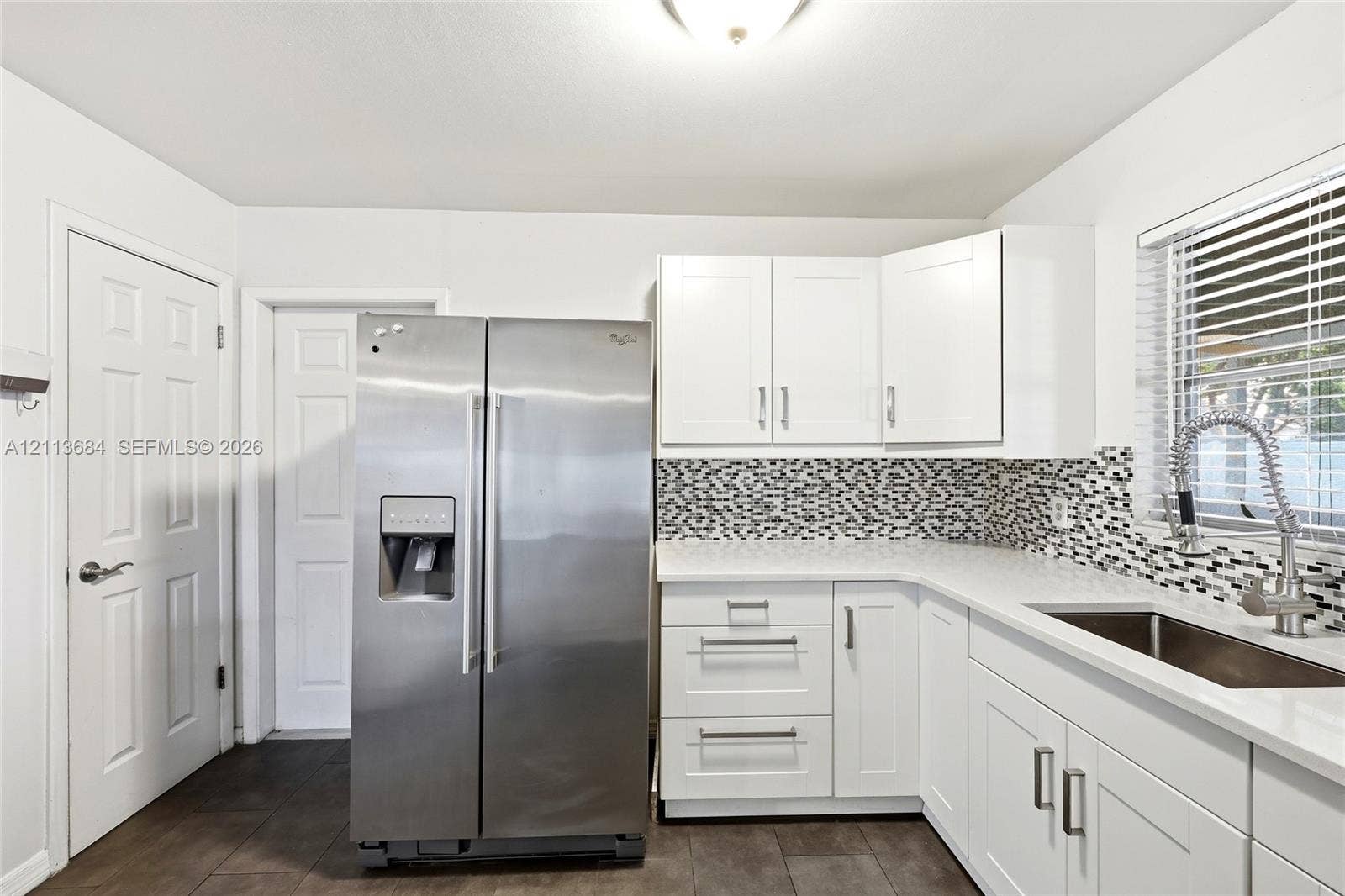 6504 Lenore Drive, Tampa, Tampa, FL 33634 Kitchen featuring white shaker-style cabinetry, stainless steel side-by-side refrigerator, mosaic tile backsplash, solid-surface countertops, and a gooseneck kitchen faucet