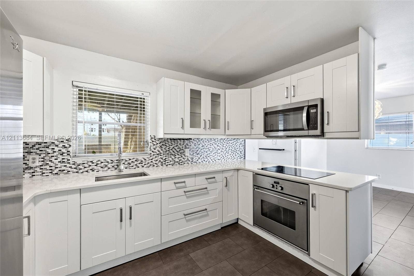6504 Lenore Drive, Tampa, Tampa, FL 33634 Kitchen featuring white shaker-style cabinetry, quartz countertops, a mosaic tile backsplash, stainless steel appliances, and large-format tile flooring