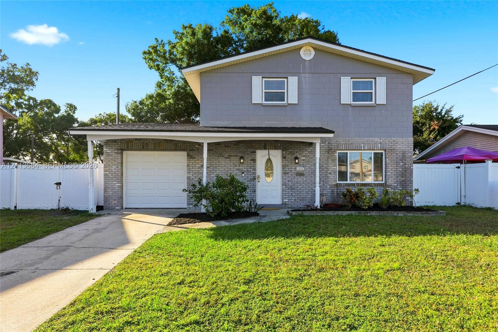 6504 Lenore Drive, Tampa, Tampa, FL 33634 Two-story exterior single-car garage, white vinyl fencing, and shuttered windows