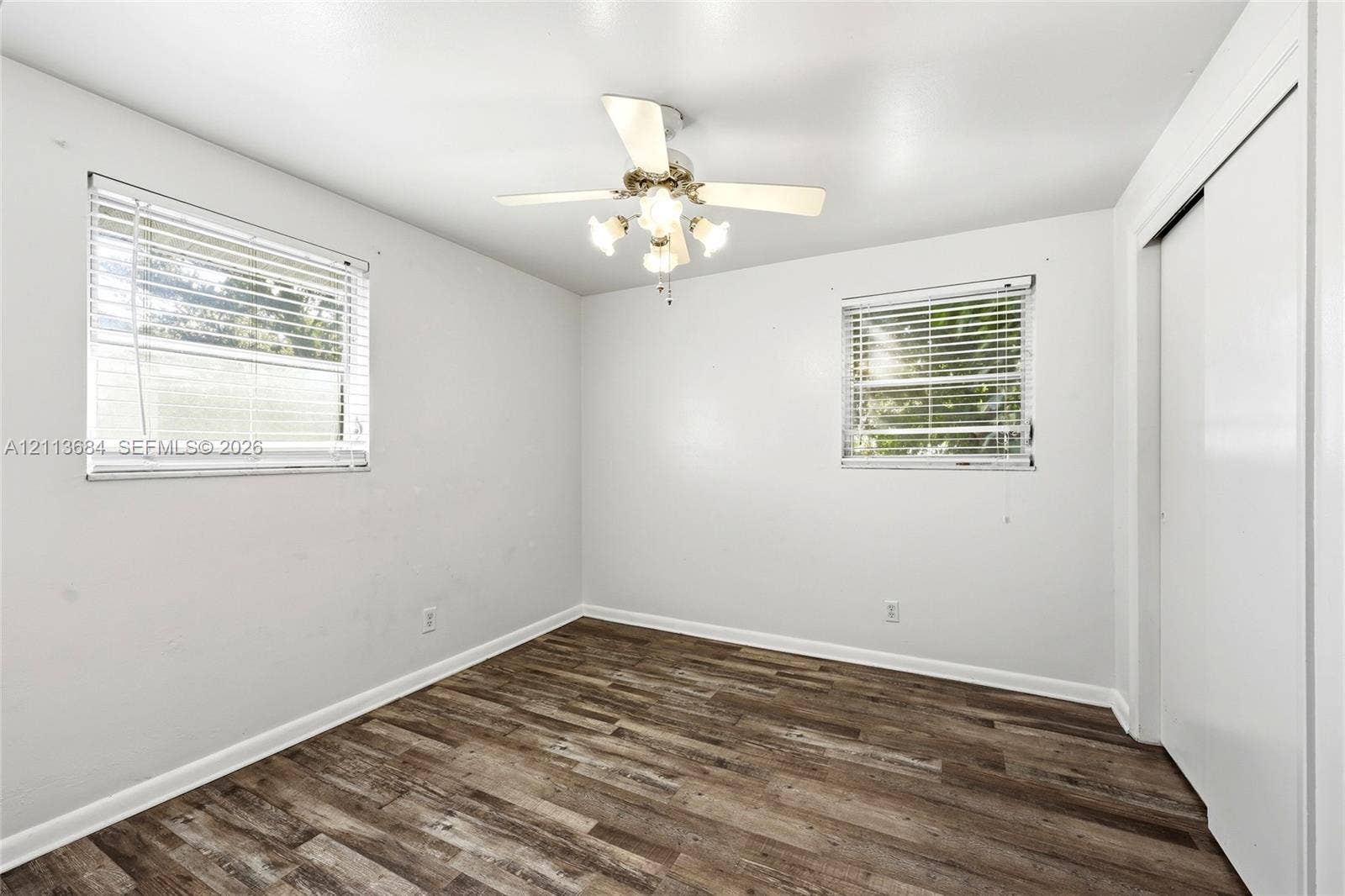 6504 Lenore Drive, Tampa, Tampa, FL 33634 Wood-finish flooring, dual windows with horizontal blinds, ceiling fan with integrated light fixture, and white closet doors