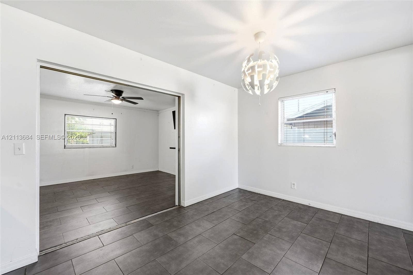 6504 Lenore Drive, Tampa, Tampa, FL 33634 Large-format ceramic tile flooring, decorative multi-tiered pendant lighting, and neutral wall finishes, complemented by horizontal sliding windows and a ceiling fan with integrated lighting