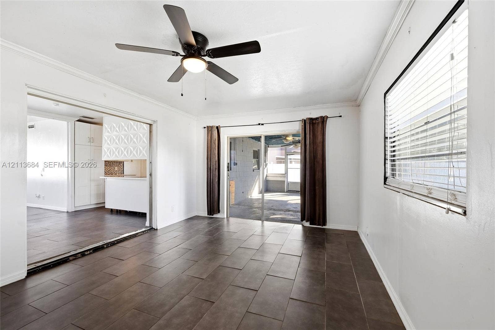 6504 Lenore Drive, Tampa, Tampa, FL 33634 Neutral-toned tile flooring, ceiling fan with integrated lighting, oversized horizontal sliding glass door, and crown molding