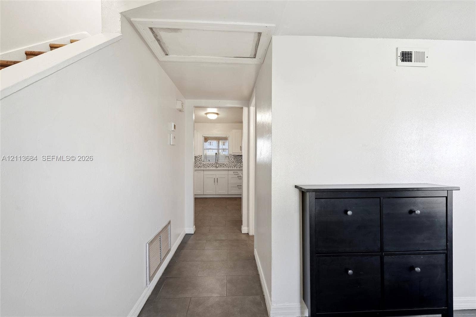 6504 Lenore Drive, Tampa, Tampa, FL 33634 Interior hallway featuring large-format grey tile flooring, neutral wall finishes, and recessed ceiling access