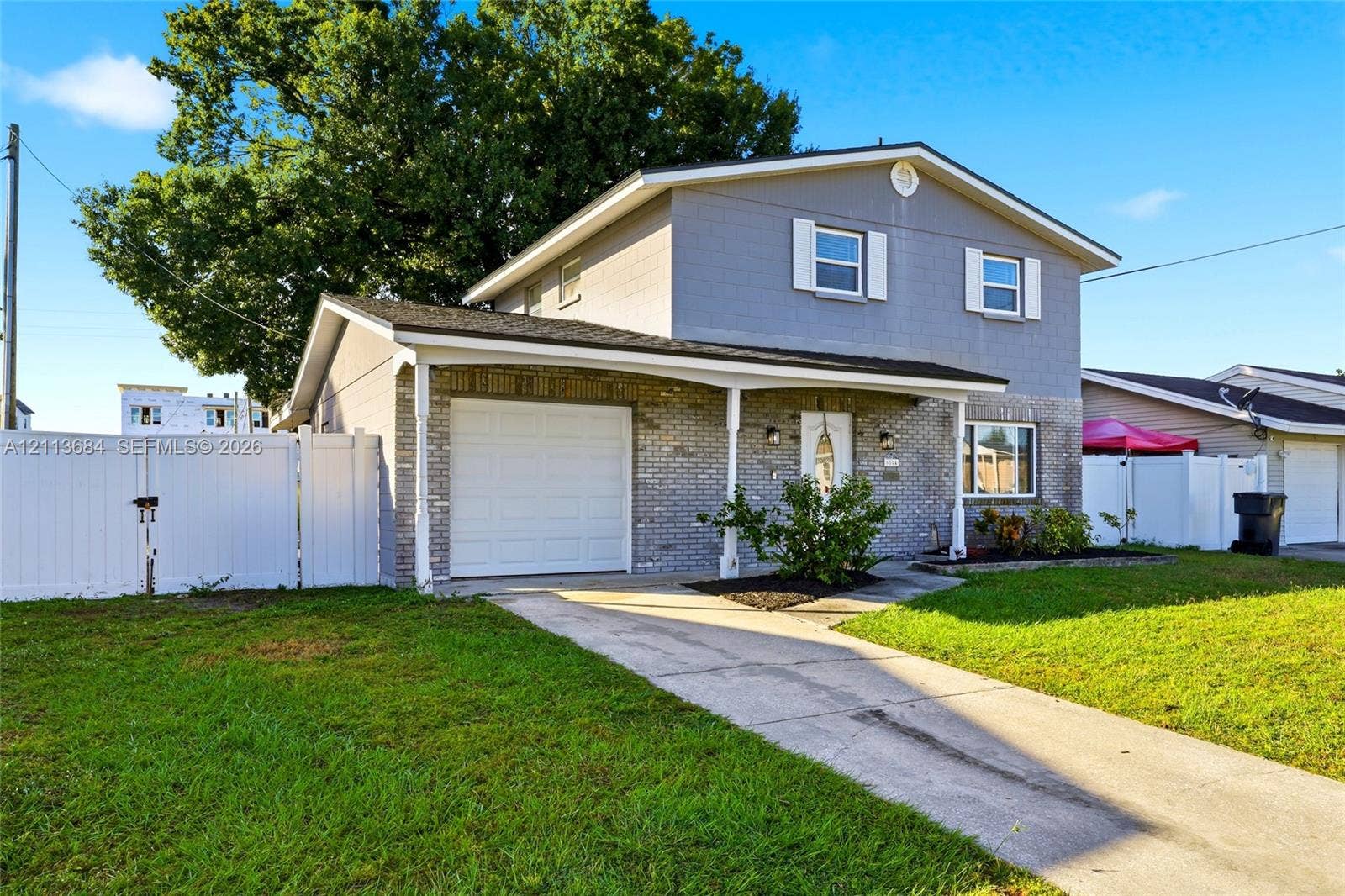 6504 Lenore Drive, Tampa, Tampa, FL 33634 Two-story residence featuring a combination of brick and lap siding exterior, an attached single-car garage, and a covered front porch with a white vinyl fence enclosure