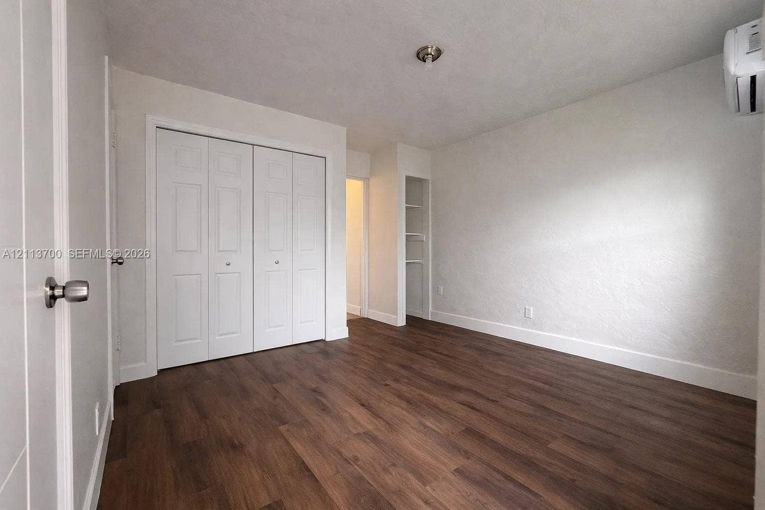 2707 Lincoln Street, #17-18, Hollywood, Hollywood, FL 33020 Interior room featuring wood-finish flooring, a wall-mounted ductless mini-split unit, white bi-fold closet doors, and recessed built-in shelving