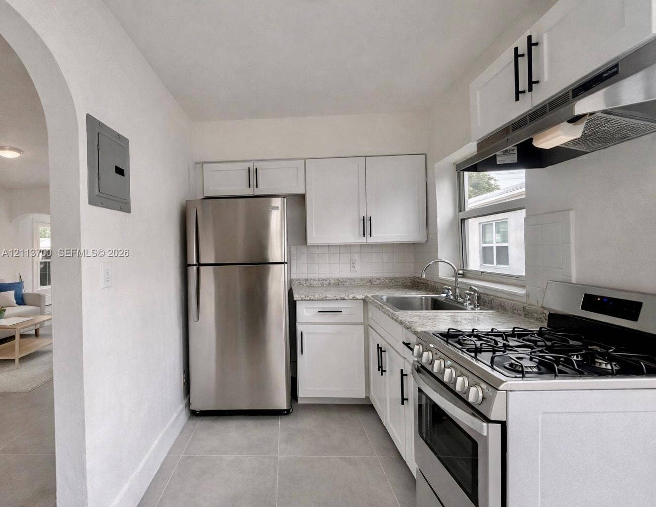 2707 Lincoln Street, #17-18, Hollywood, Hollywood, FL 33020 Kitchen featuring white shaker-style cabinetry with matte black hardware, stone-patterned countertops, stainless steel appliances, and large-format tile flooring
