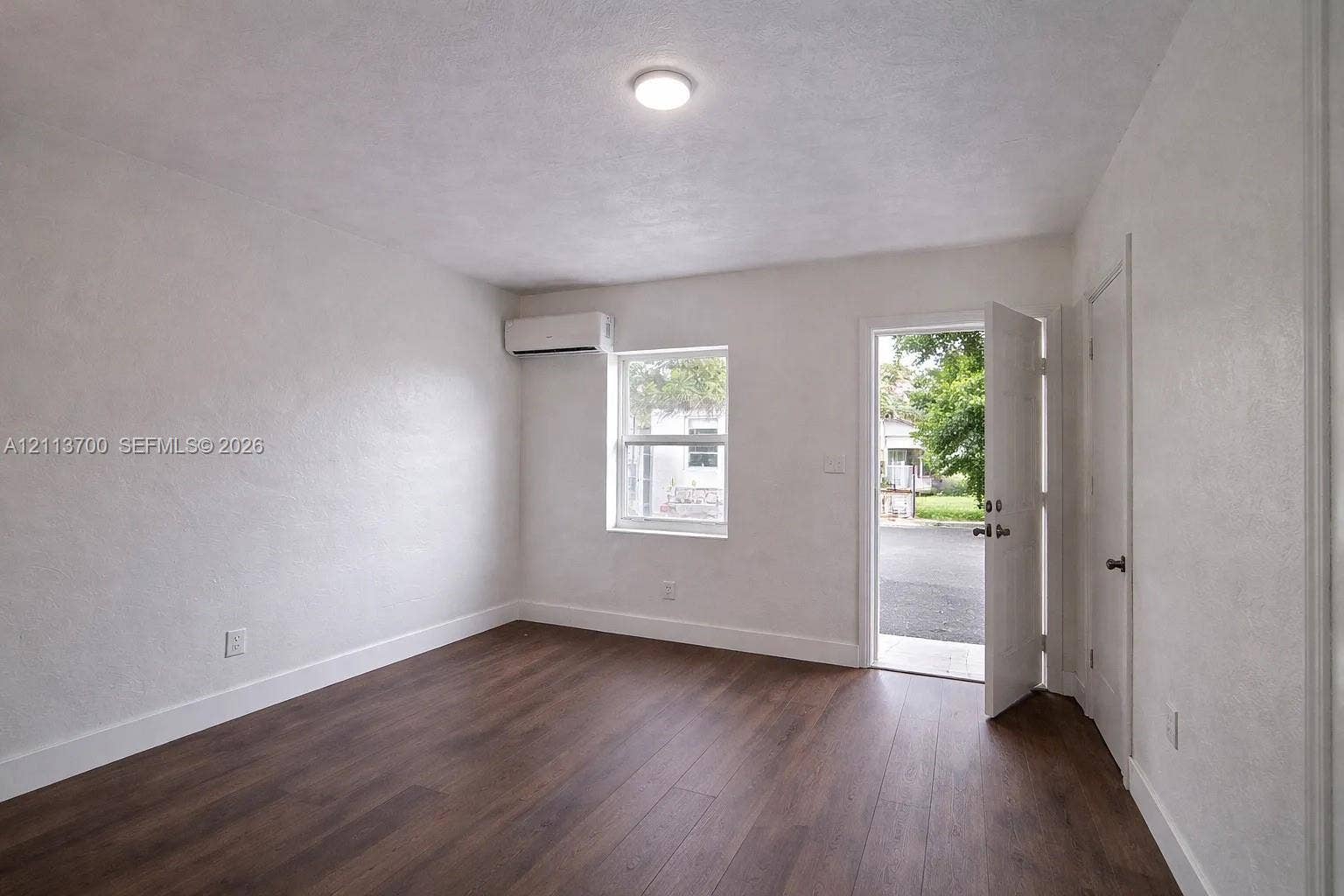 2707 Lincoln Street, #17-18, Hollywood, Hollywood, FL 33020 Room featuring wood-finish flooring, a wall-mounted ductless mini-split climate control unit, a single-hung window, and a flush-mount ceiling light fixture