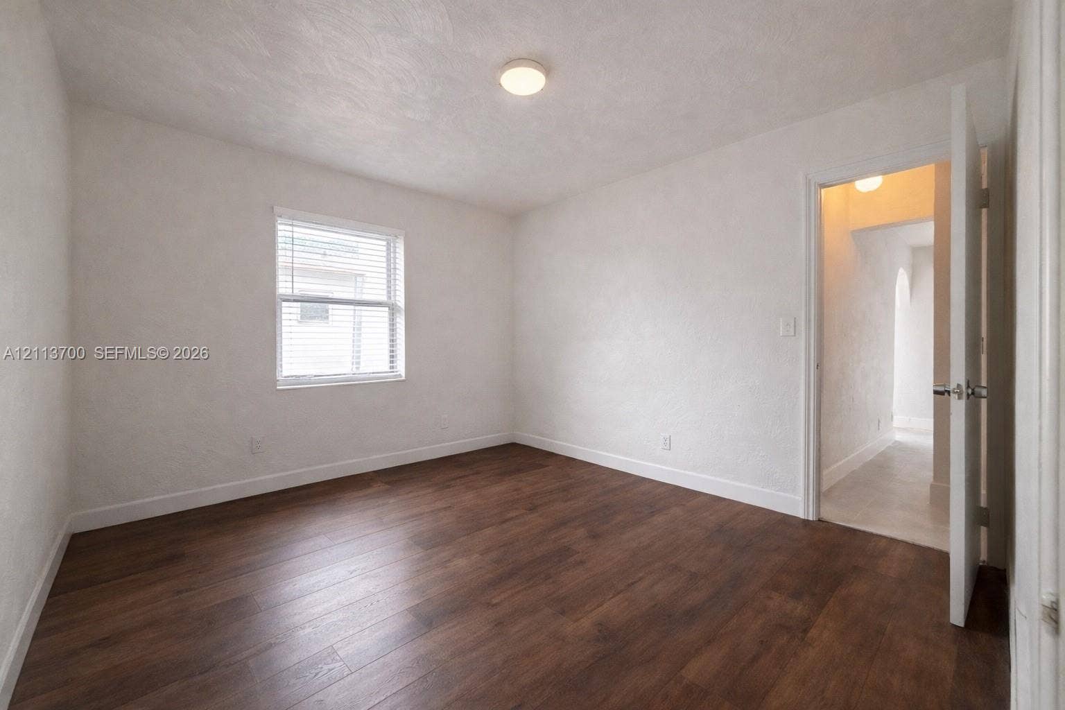 2707 Lincoln Street, #17-18, Hollywood, Hollywood, FL 33020 Interior room featuring wood-finish flooring, white textured walls, a single-hung window with horizontal blinds, and a flush-mount ceiling light