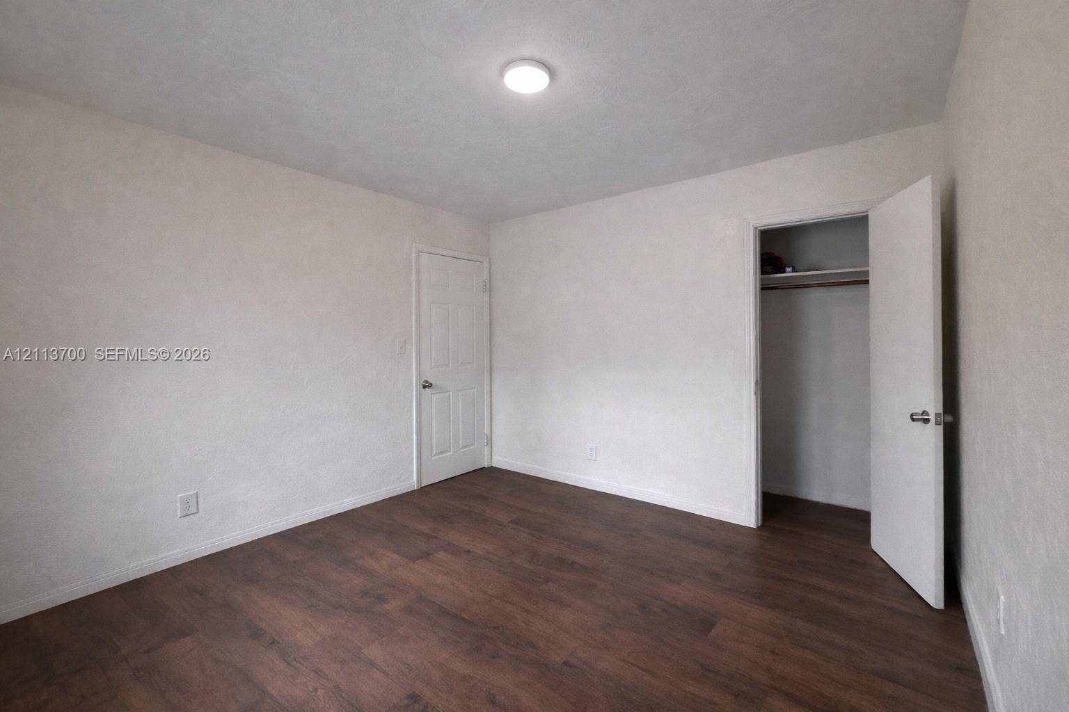 2707 Lincoln Street, #17-18, Hollywood, Hollywood, FL 33020 Neutral-toned interior space featuring wood-finish flooring, a recessed closet with built-in shelving, a panel door, and a flush-mount ceiling light fixture