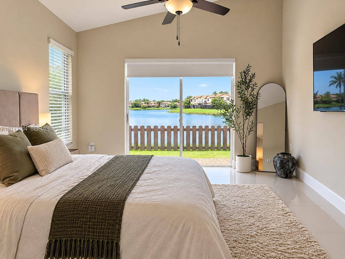 5254 SW 153rd Court, Miami, FL 33185 Vaulted ceiling with integrated lighted ceiling fan, tile flooring, and sliding glass doors opening to a waterfront backdrop