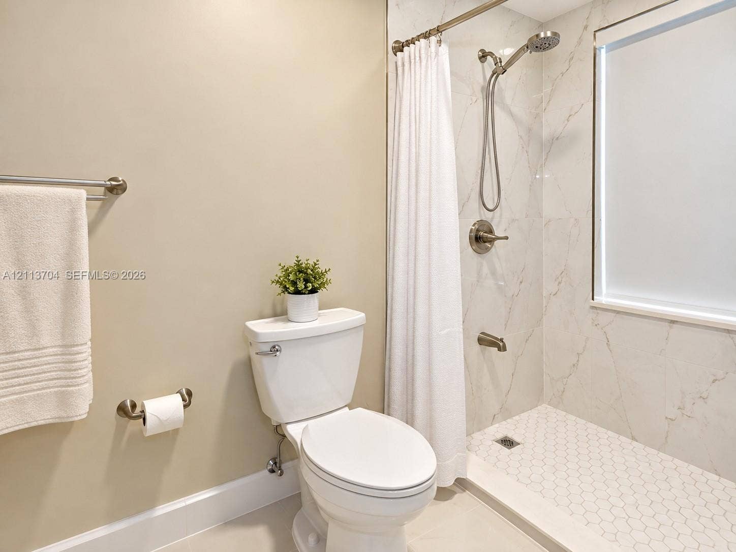 5254 SW 153rd Court, Miami, FL 33185 Full bathroom featuring large-format wall tile with natural veining, a hexagonal tile shower floor, brushed-finish fixtures, and a glass-enclosed window
