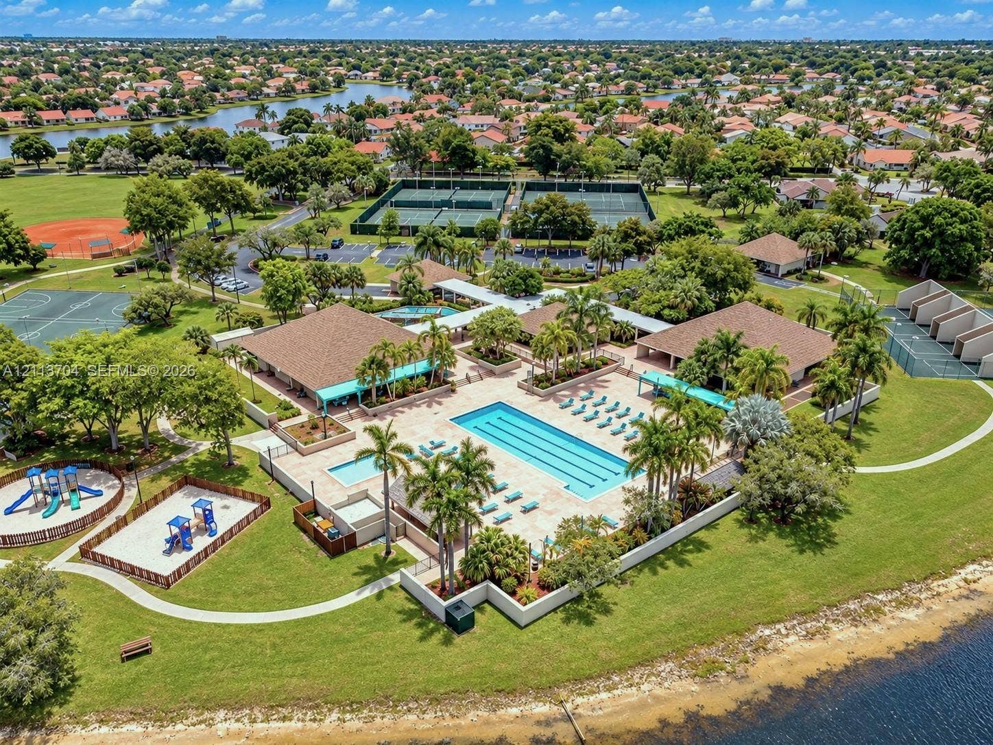 5254 SW 153rd Court, Miami, FL 33185 Community recreation complex featuring a lap-style swimming pool, multiple tennis courts, a basketball court, and a playground area, all situated within a waterfront setting