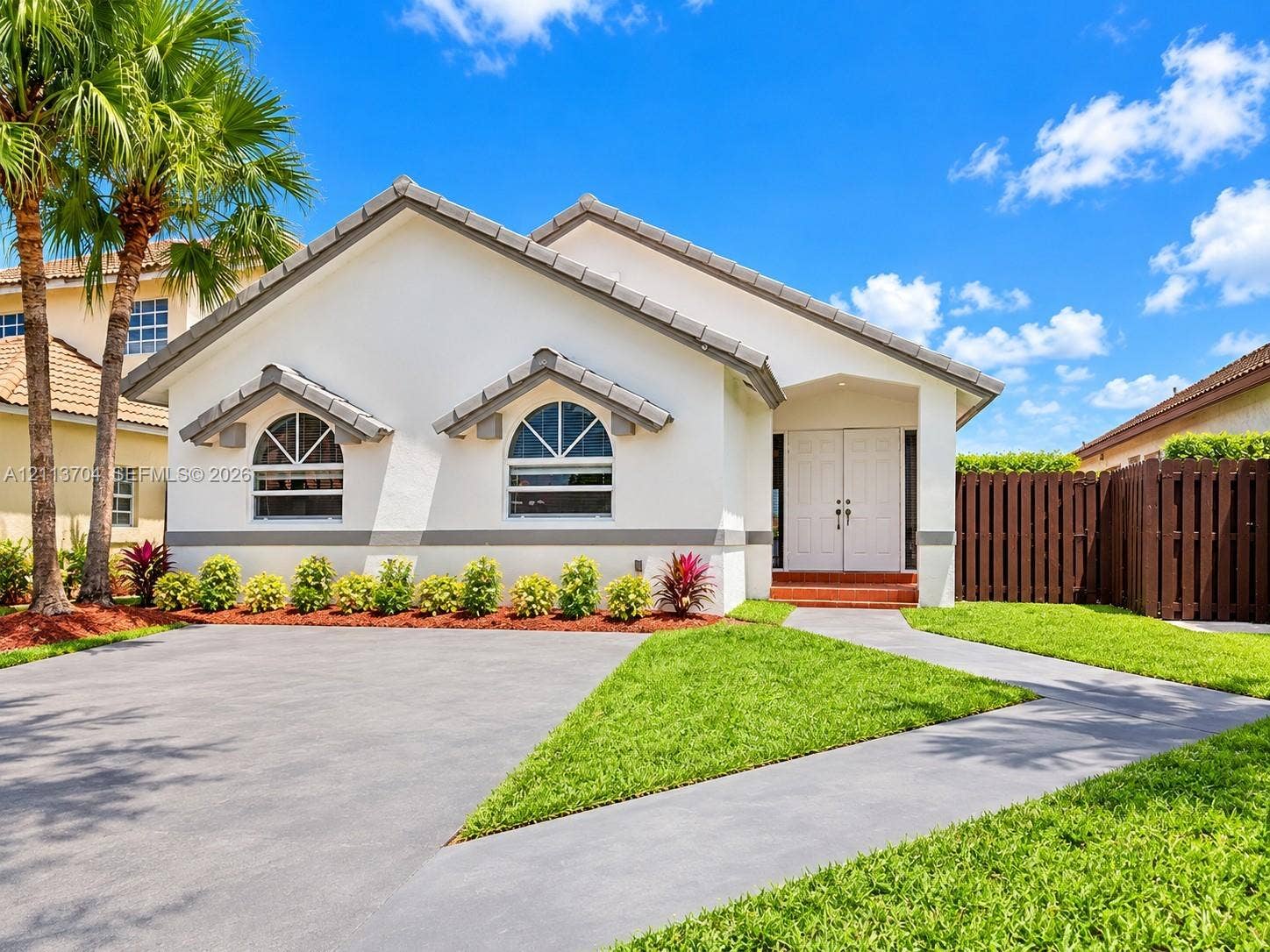 5254 SW 153rd Court, Miami, FL 33185 Single-story residence featuring a tile roof, stucco exterior, arched windows, dual-entry doors, and a concrete driveway