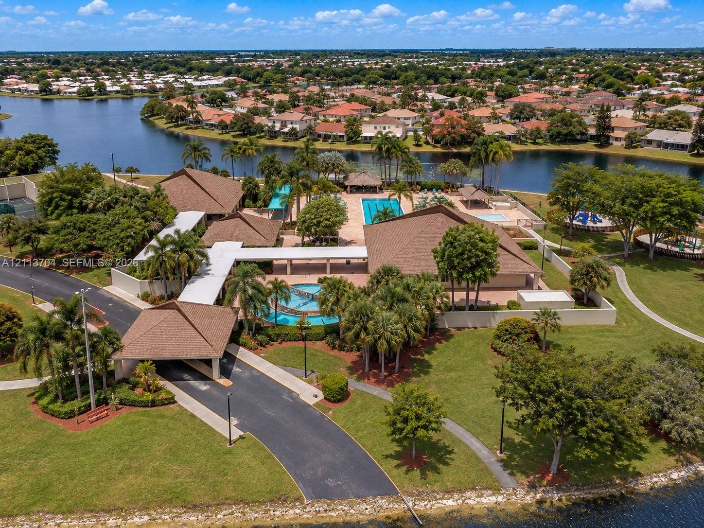 5254 SW 153rd Court, Miami, FL 33185 Community center featuring a multi-building complex, outdoor swimming pool, fountain, paved walkways, and lakefront grounds